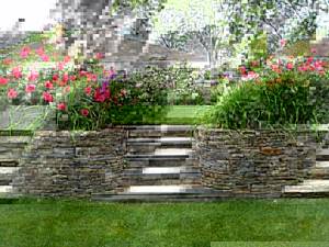 Две каменные клумбы с цветами обрамляют садовые ступеньки